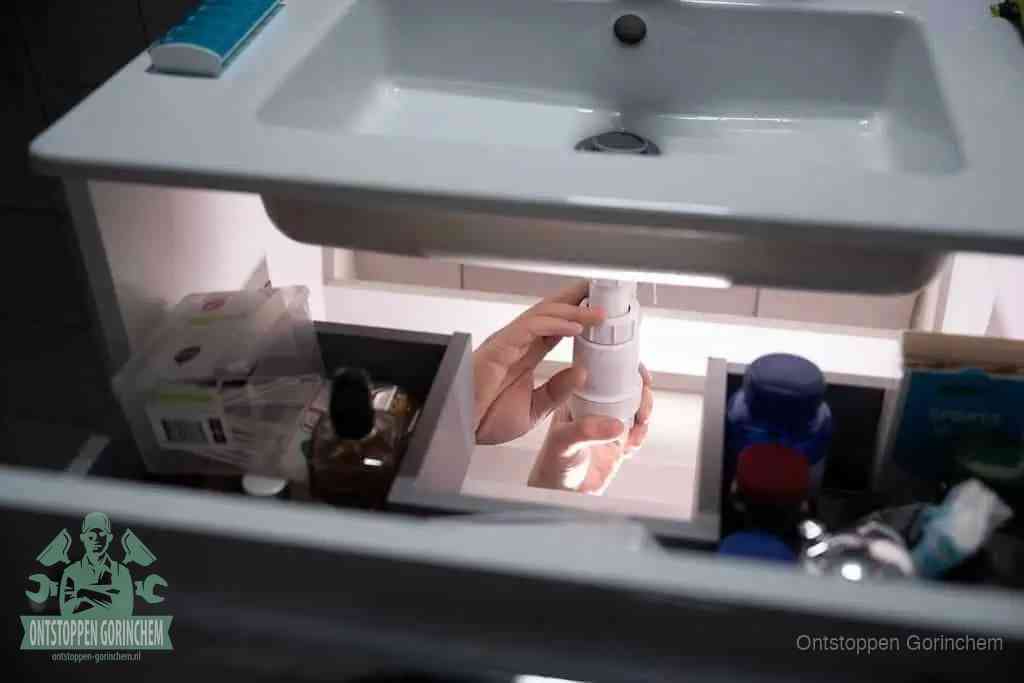 Een pompfles met zeep boven een wastafel, de heet water en afwasmiddel-methode om een vetprop in de afvoer los te maken in Gorinchem