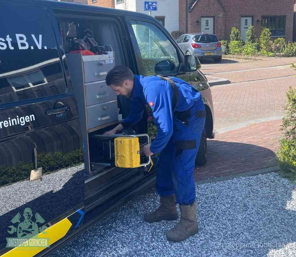 Een monteur pakt buiten op de oprit gereedschap uit de bedrijfsbus, het moment om een professional in te schakelen voor een verstopte afvoer in Gorinchem