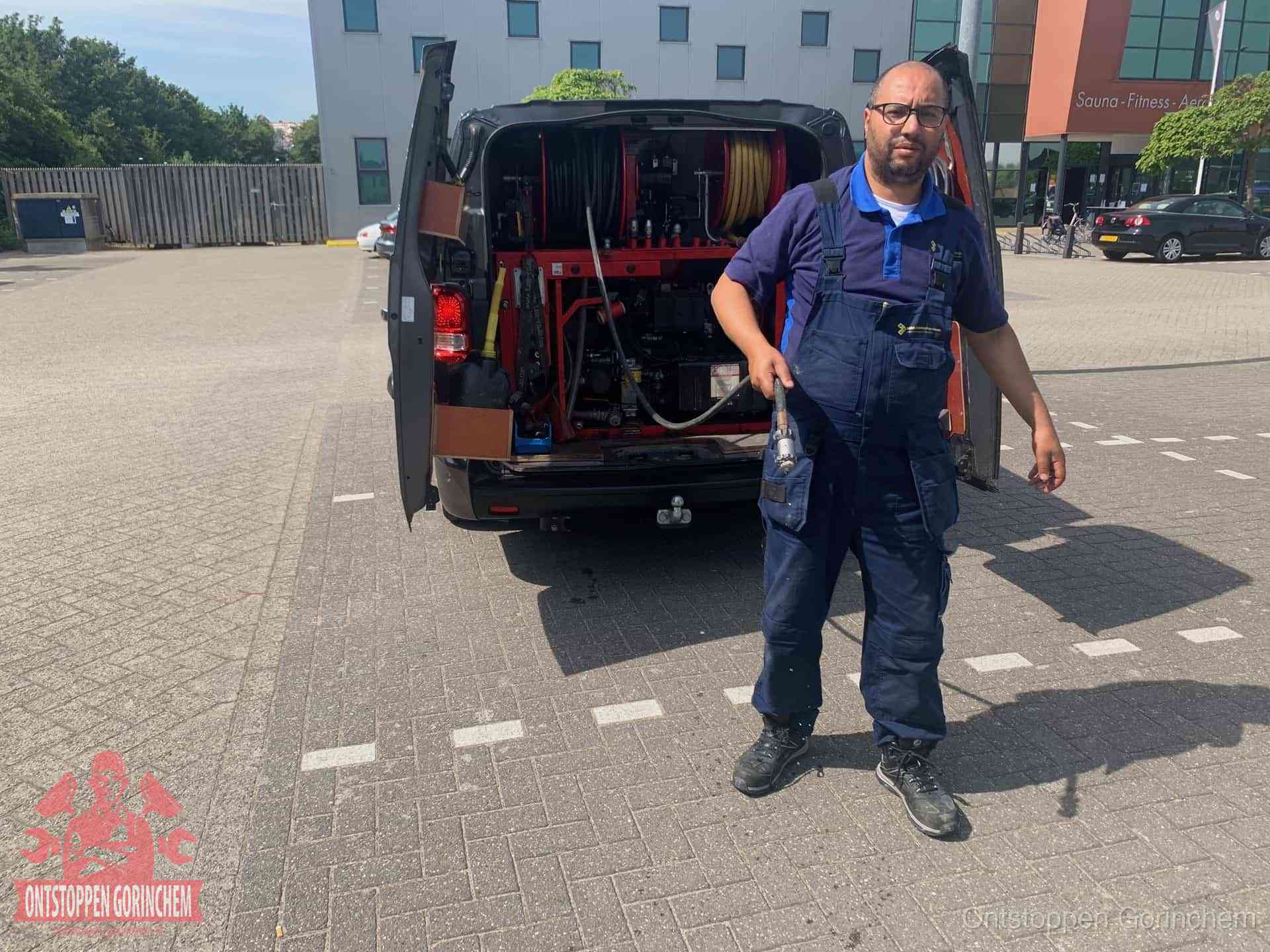 Een monteur bij zijn bestelbus met een hogedruk- en rioolreinigingsunit, klaar om de oorzaak van terugkerende wc-verstoppingen aan te pakken in Gorinchem