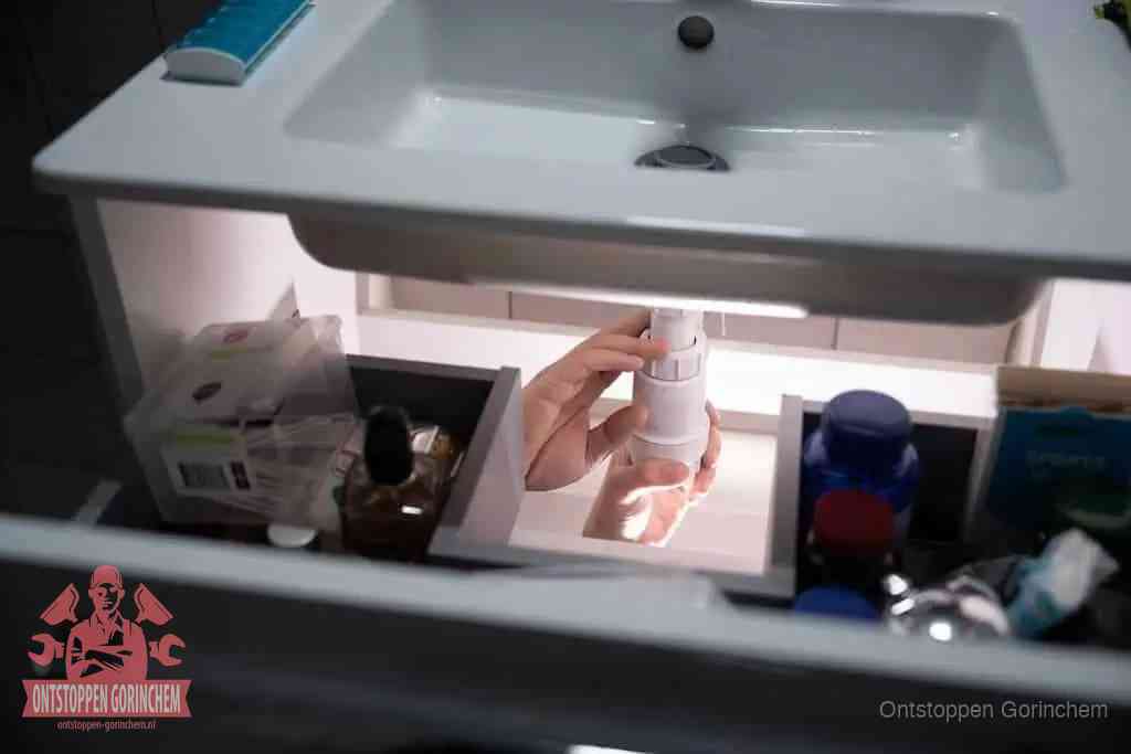 Een pompfles met zeep boven een wastafel in de toiletruimte, de warm water en afwasmiddel-methode om de wc te ontstoppen in Gorinchem