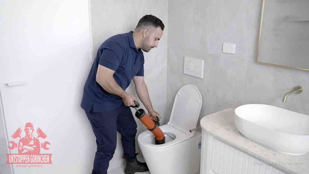Een monteur gebruikt een handmatige perspomp (toiletontstopper) op een wandcloset tijdens het professioneel wc ontstoppen in Gorinchem